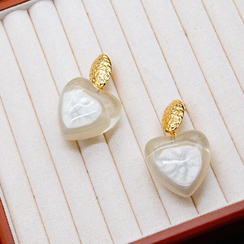 Heart-shaped earrings with gold accents on a white jewelry display box.