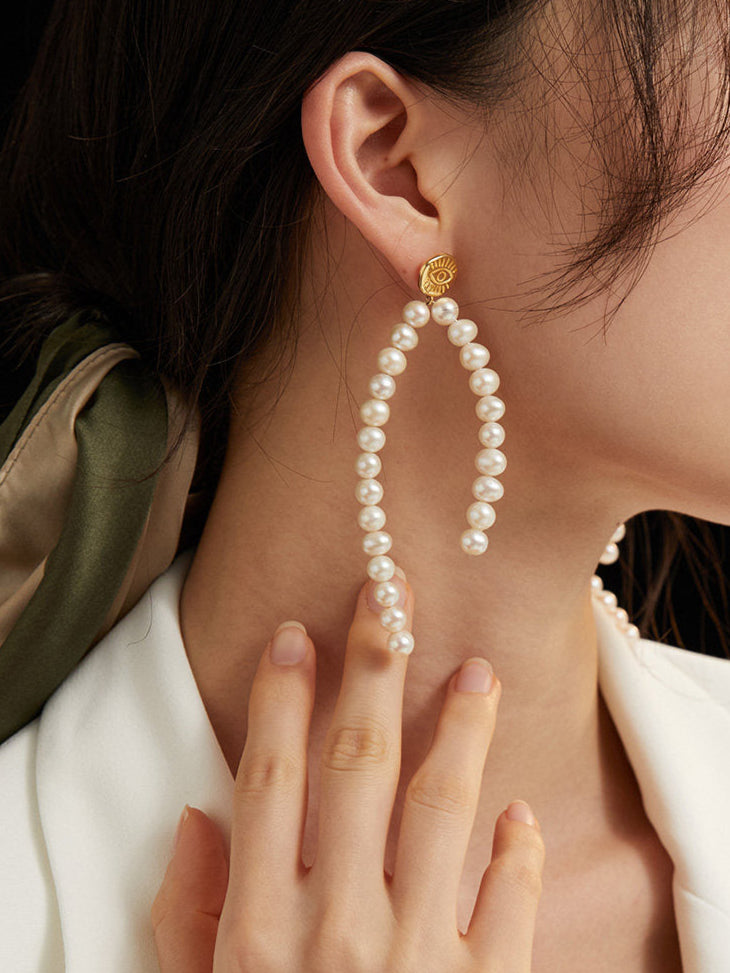 Close-up of a woman wearing pearl earrings with a dark background